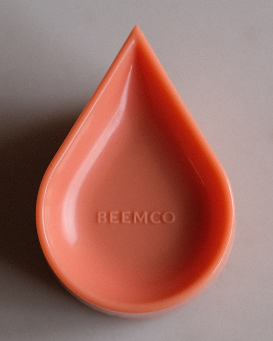 Papaya coloured teardrop-shaped object with 'BEEMCO' branding on a gray background